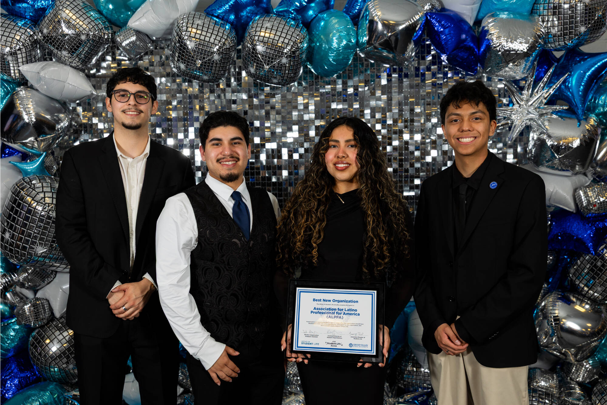 Four individuals holding an award certificate